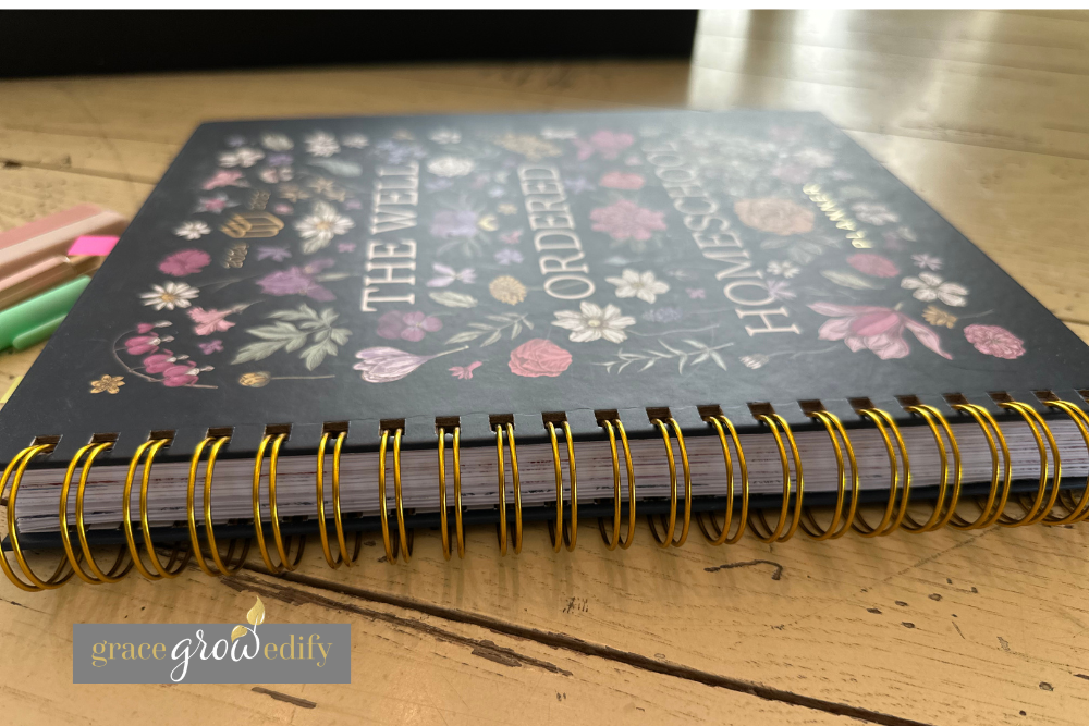Flat lay Side view photo of The Well Ordered Homeschool Planner showing the metal coil binding that lays flat for easy homeschool planning.